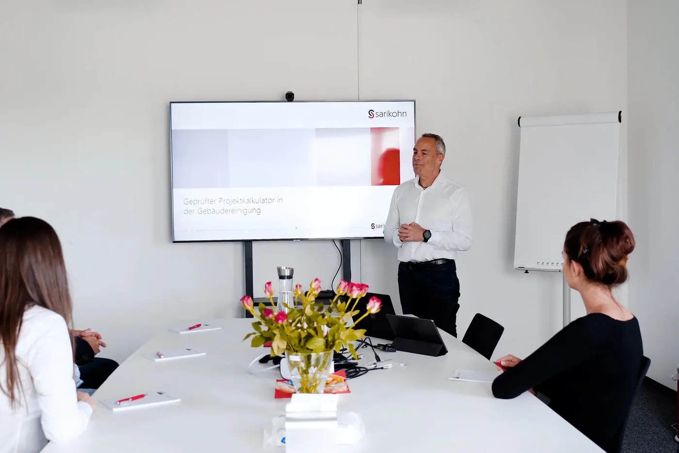 Seminar zur Projektkalkulation: Vortrag vor der Titelfolie des Lehrgangs, Teilnehmende am Tisch